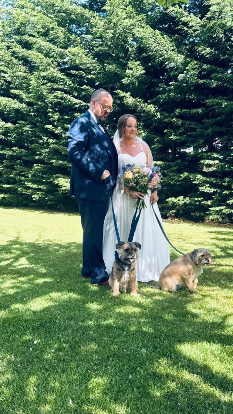 Bride and groom posing with their two dogs on their wedding day with the help of a Pets 2 Places dog wedding chaperone service
