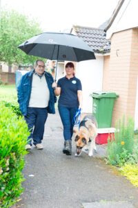 pet taxi franchisee assisting customer to the taxi with umbrella to shelter from rain