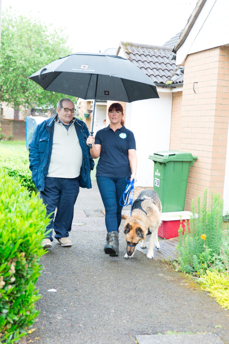 pet taxi driver assisting customer to the taxi with umbrella to shelter from rain